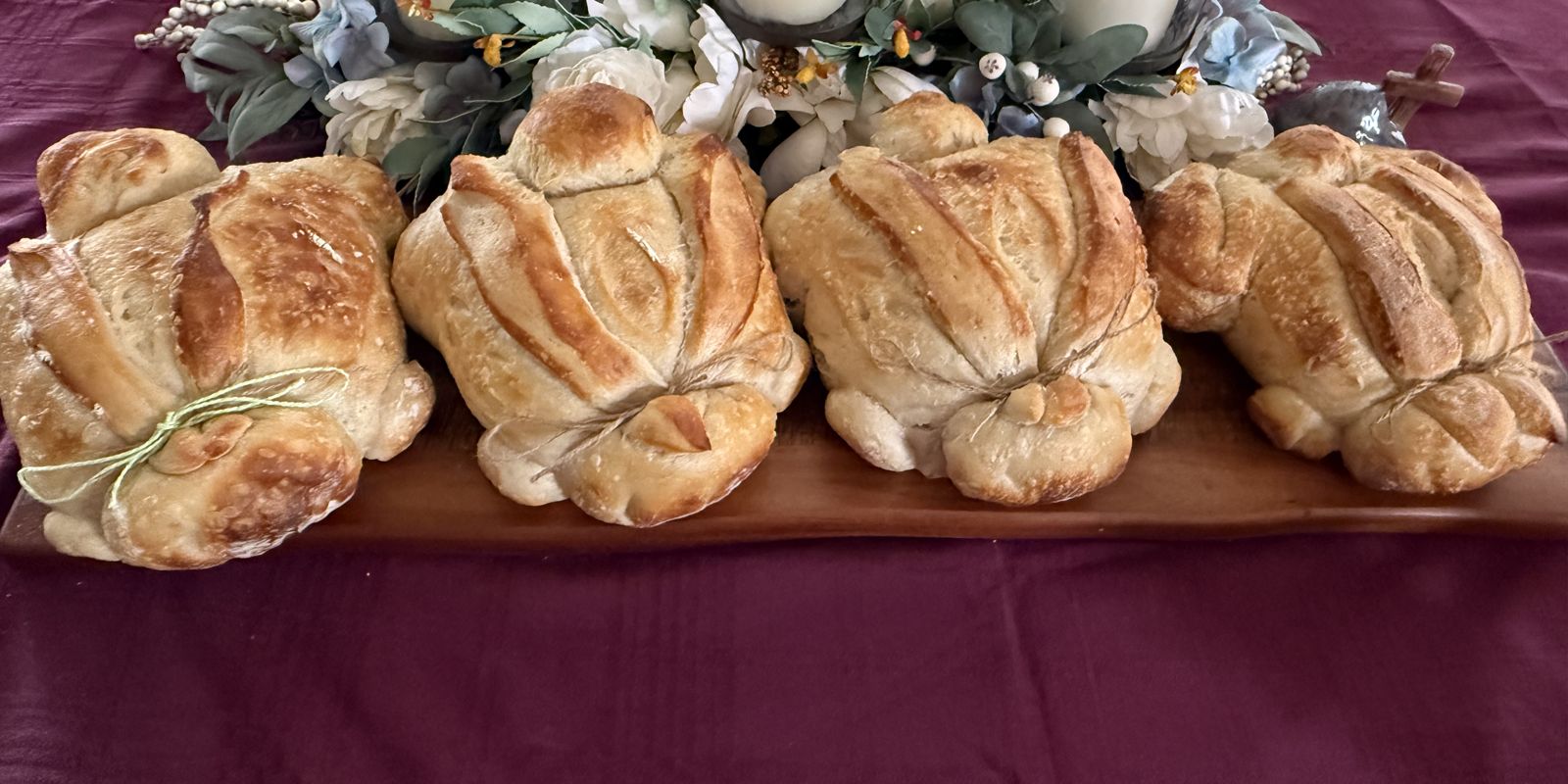 Four shaped sourdough loaves tied with twine on a wooden board